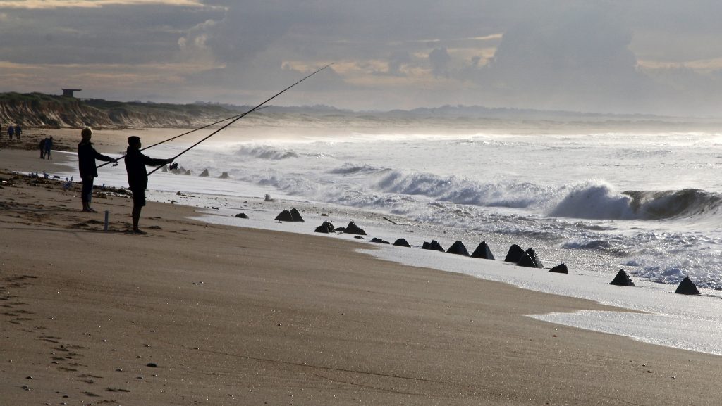 Historic Stockton tank traps, concrete pyramid-shaped structures lined along the sandy beach, once used as coastal defense during World War II.