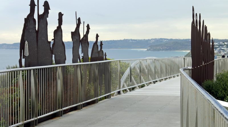 Newcastle Memorial Walk bridge above the ocean cliffs. Steel soldier silhouettes line the walkway, engraved with the names of soldiers from the region who enlisted in WW1.